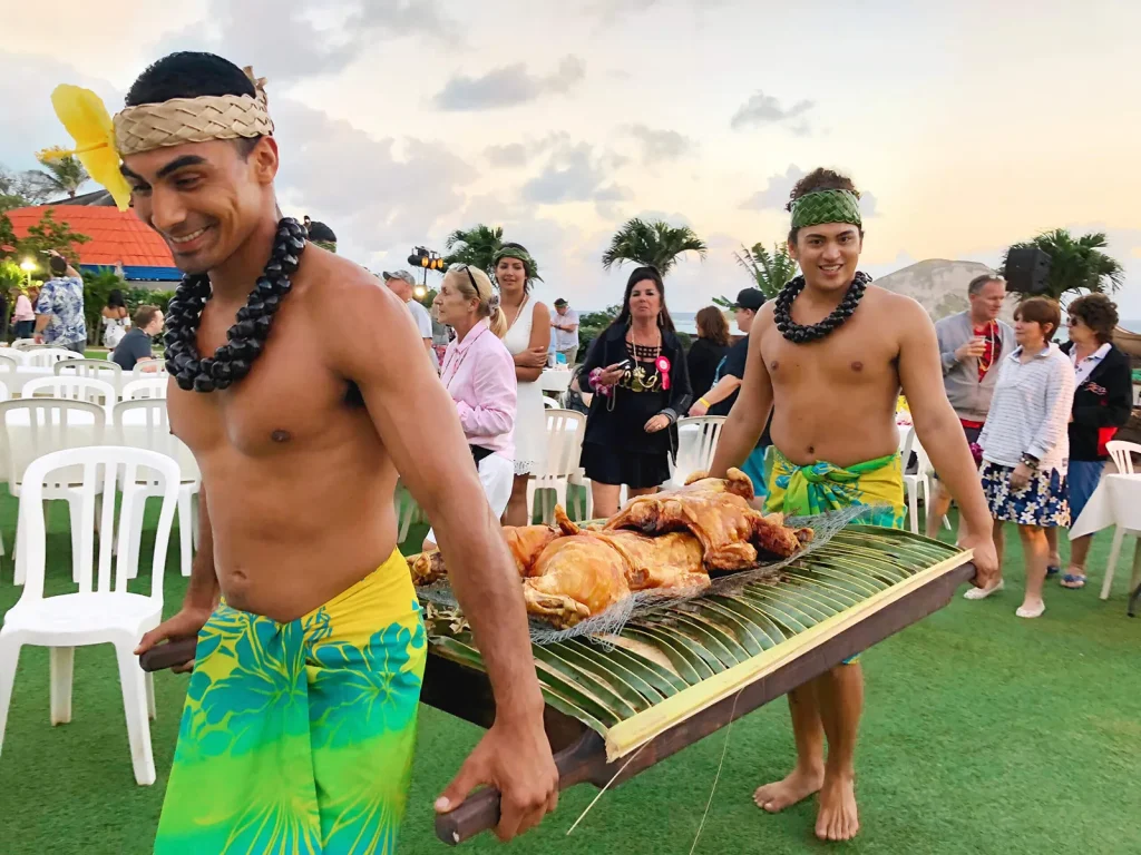 イム(ハワイ伝統のかまど)で蒸し上げた豚を運ぶダンサーたち