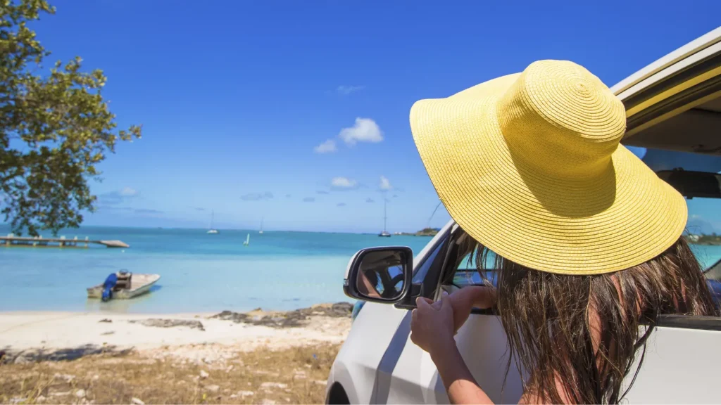 ビーチパークで車を停めて海を眺める女性/アラモレンタカー